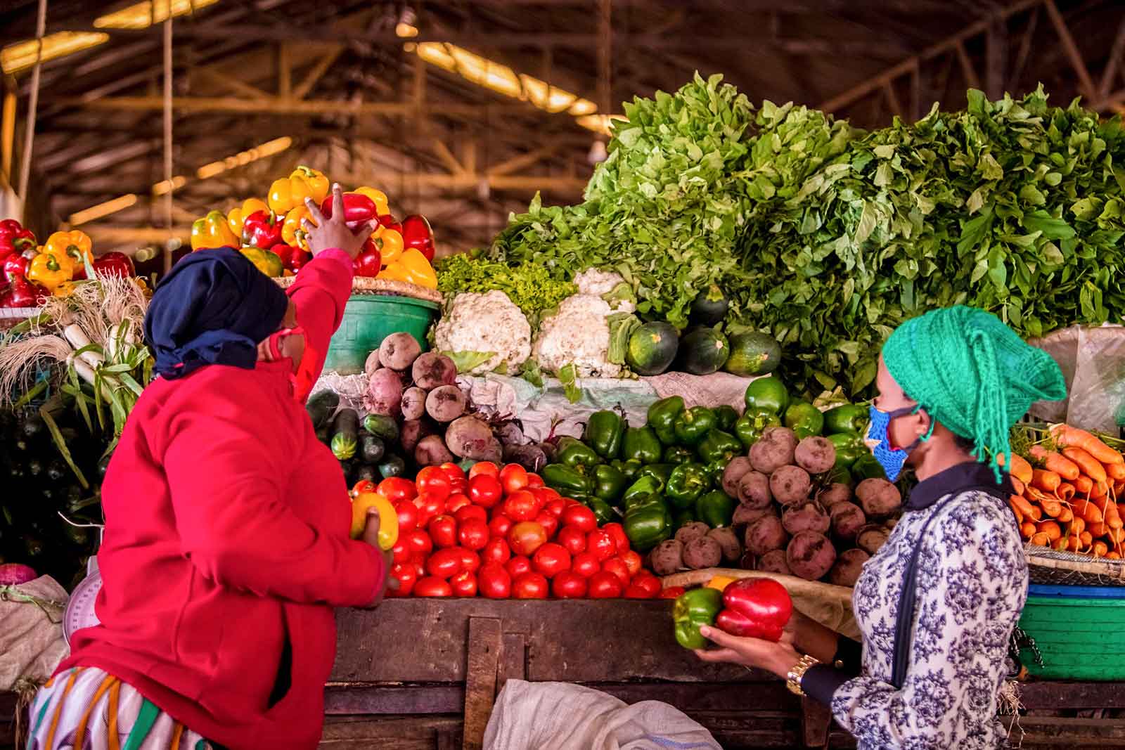 A woman picks up vegetables in Kimironko Market in Kigali. Walk through Kigali markets for a local market experience.